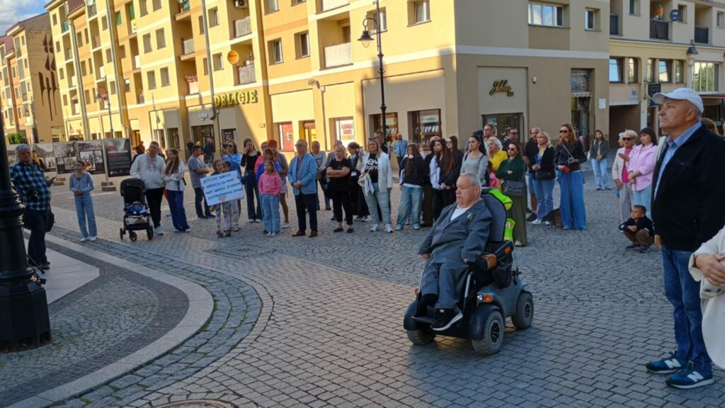 Grupa ludzi na legnickim rynku. Mężczyzna na wózku z przodu.